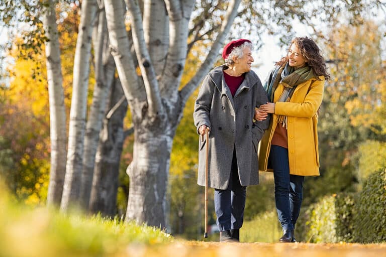 Two women walking in a vibrant autumn park