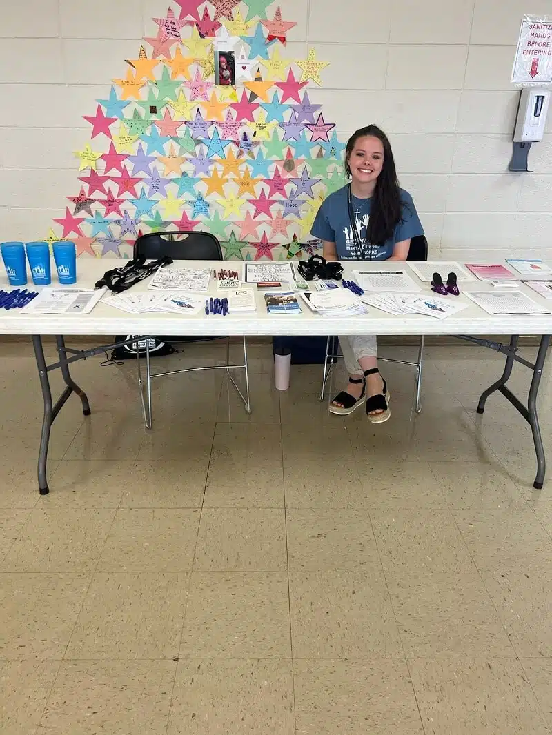 Staff member at a table with promotional materials.