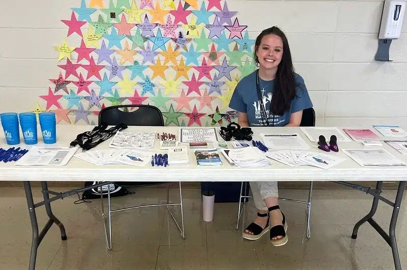 Staff member at an informational table with colorful background