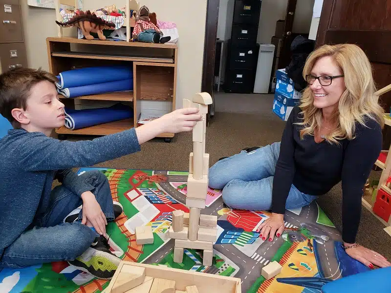 Child and adult playing with building blocks indoors.