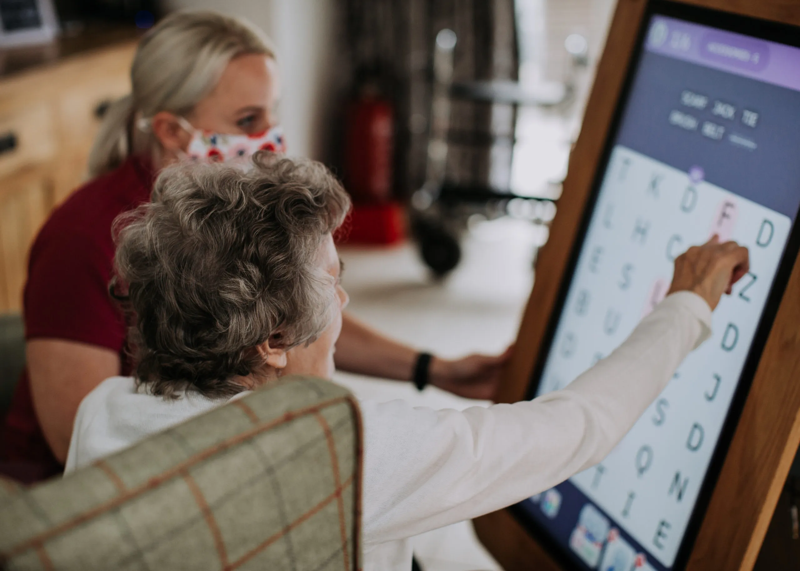 Senior interacting with staff using touchscreen technology.