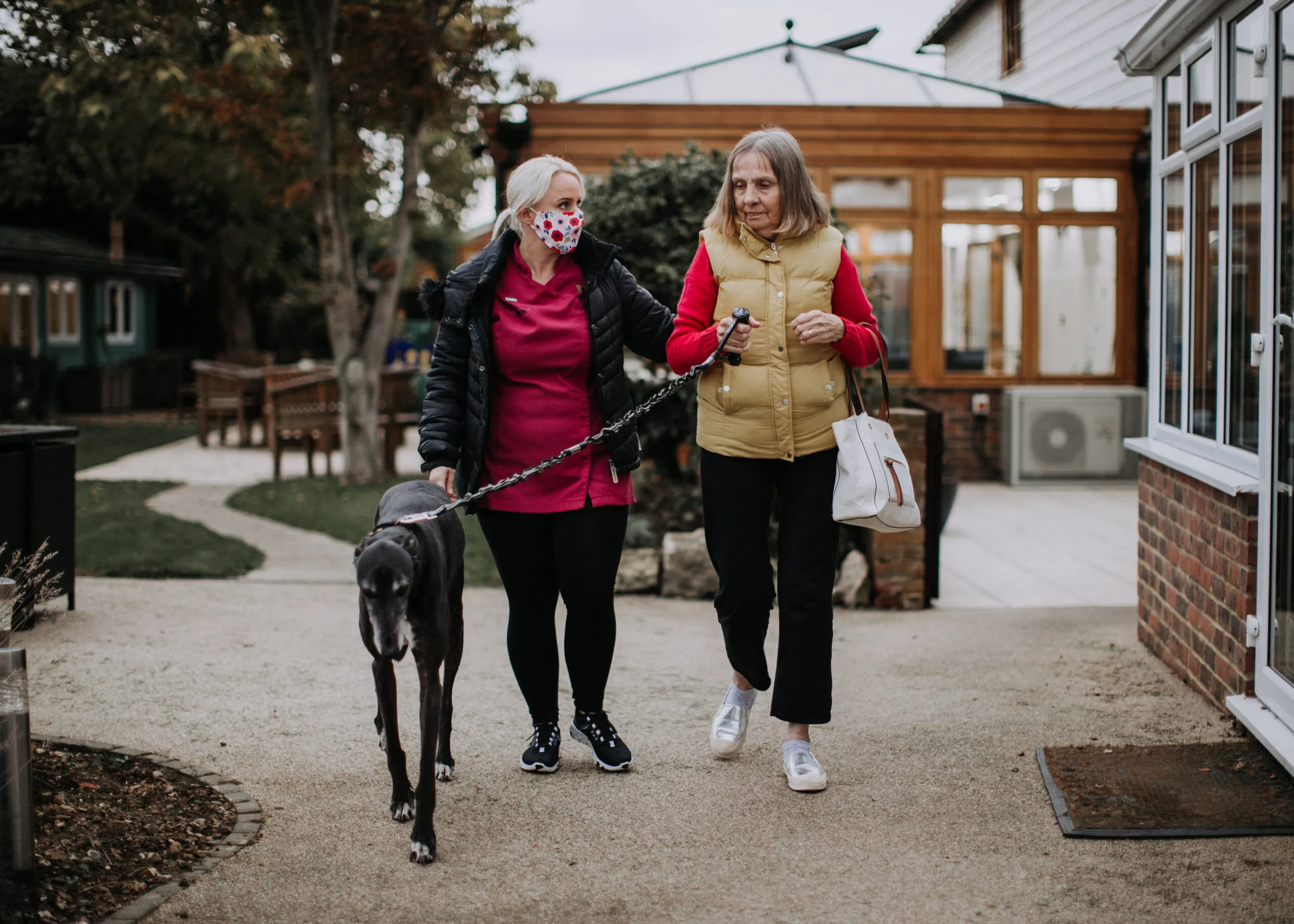 A woman walking with a resident and a dog outdoors.