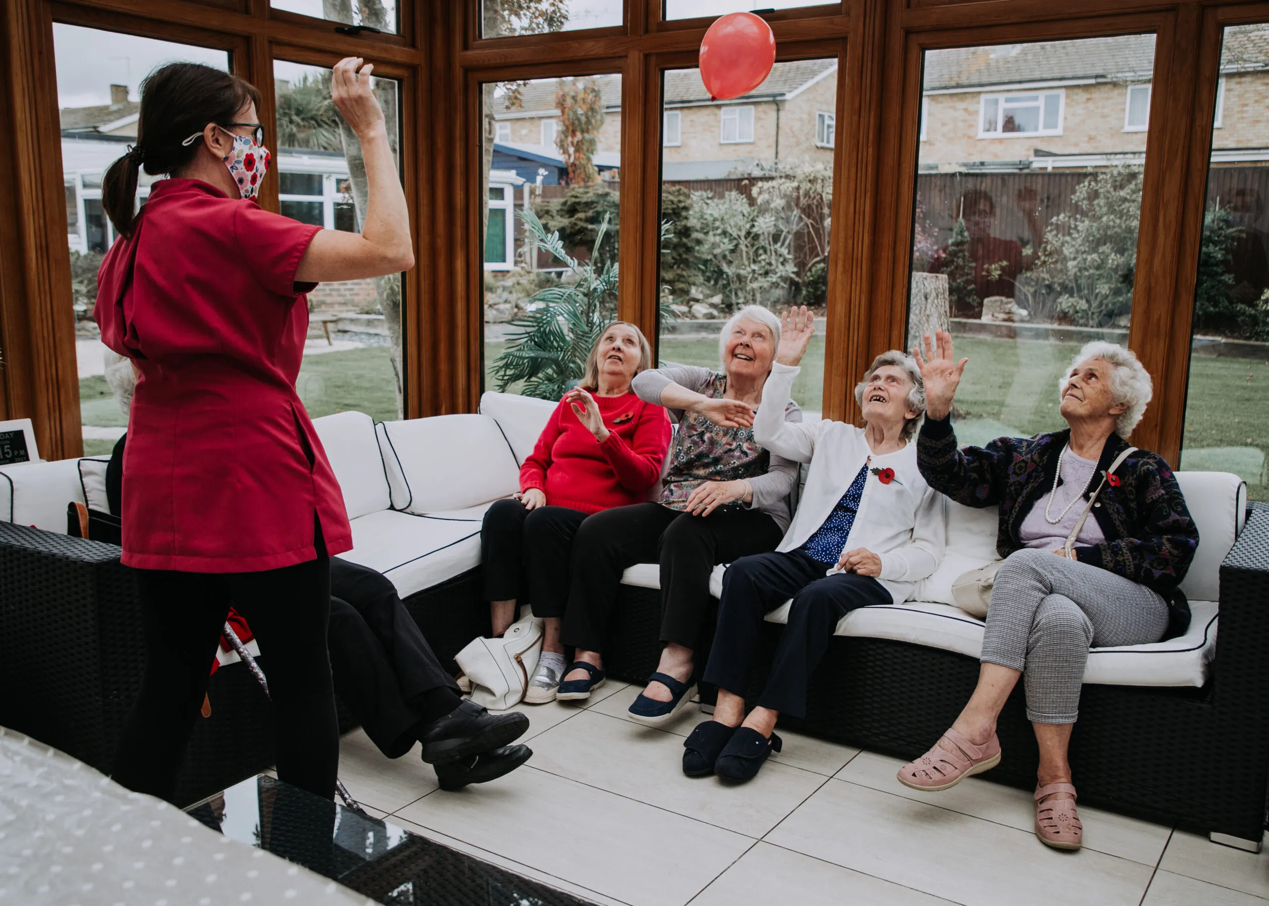 Residents and staff play with a balloon in a common area.