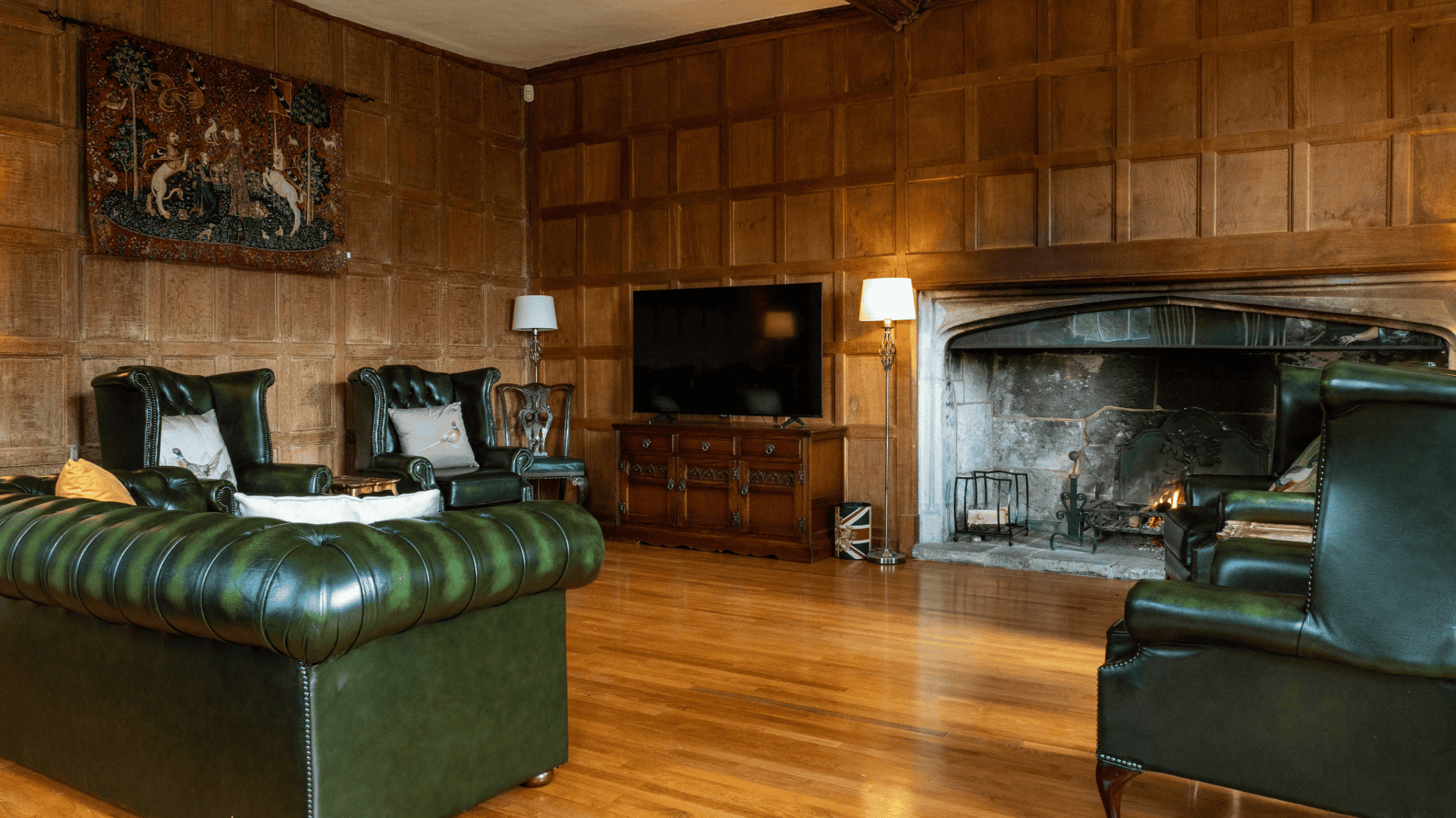 Cozy common area with green leather seating and a fireplace.