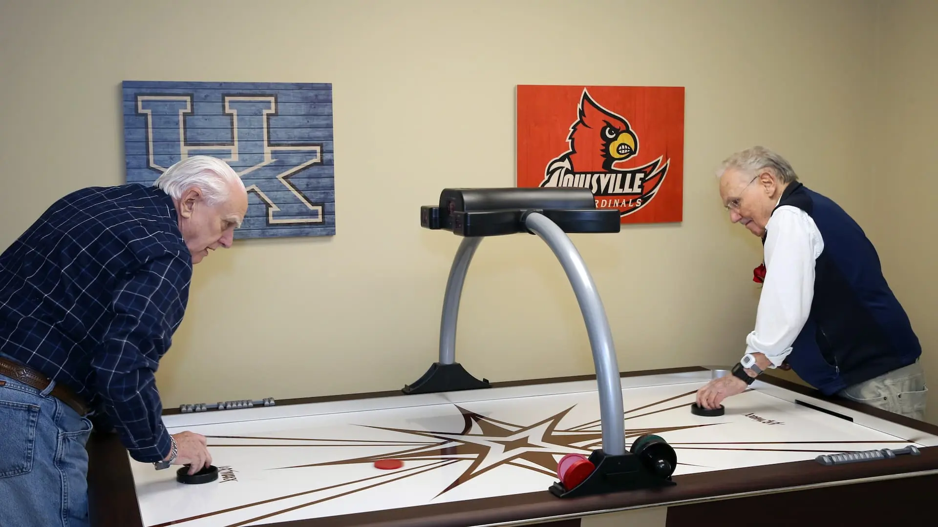 Two residents playing air hockey in a common area