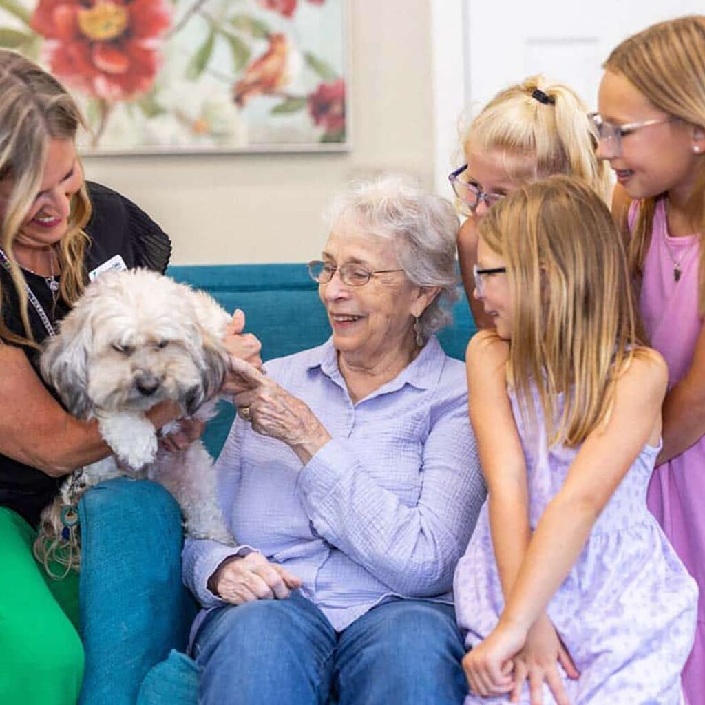 A senior resident enjoying time with children and a dog