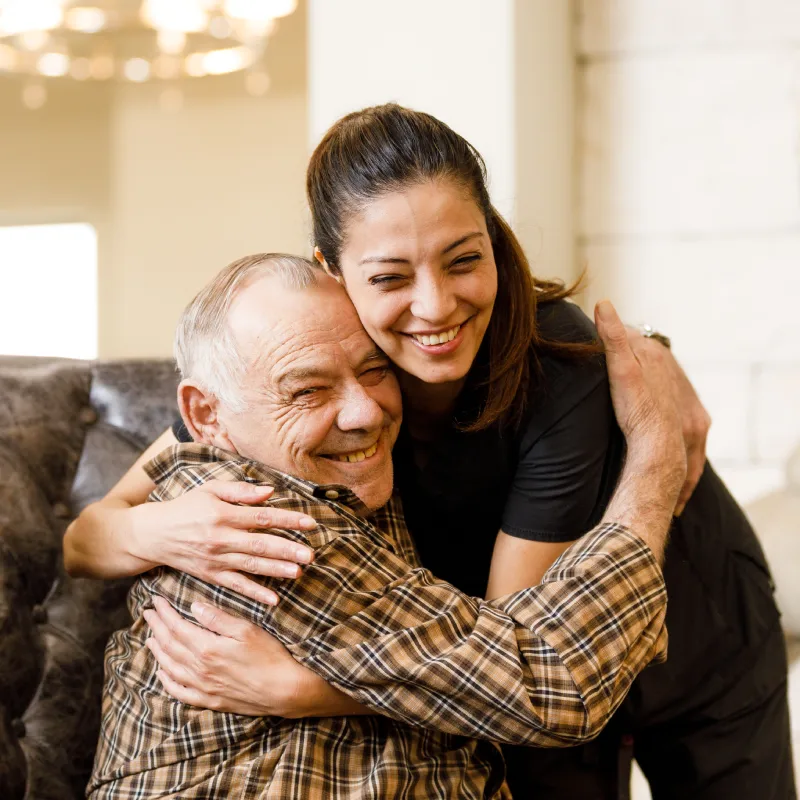 A resident and staff member sharing a joyful hug