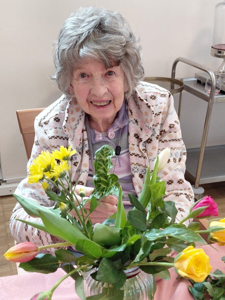 Resident at a table with colorful flowers.
