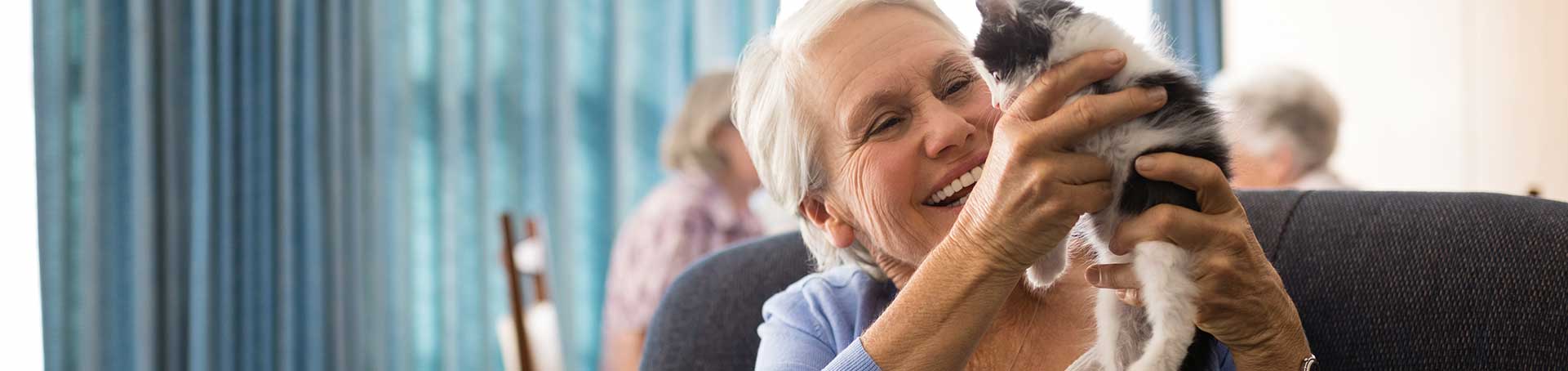 Senior woman joyfully holding a kitten
