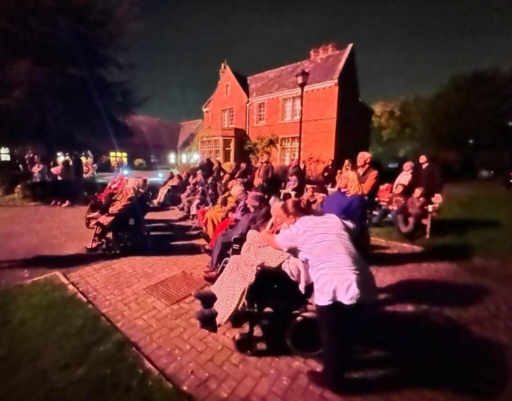 Residents enjoying an outdoor event under the night sky.