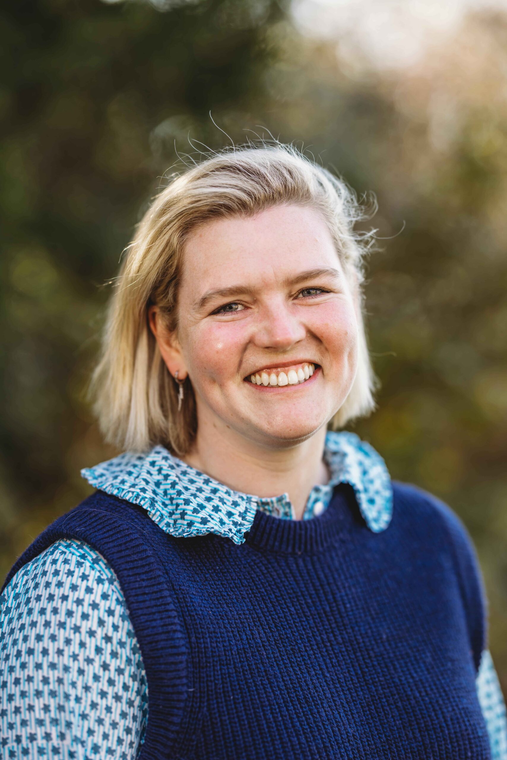 Smiling staff member outdoors with a blurred background.