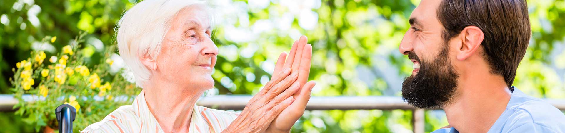 Older woman and caregiver sharing a joyful moment outdoors.