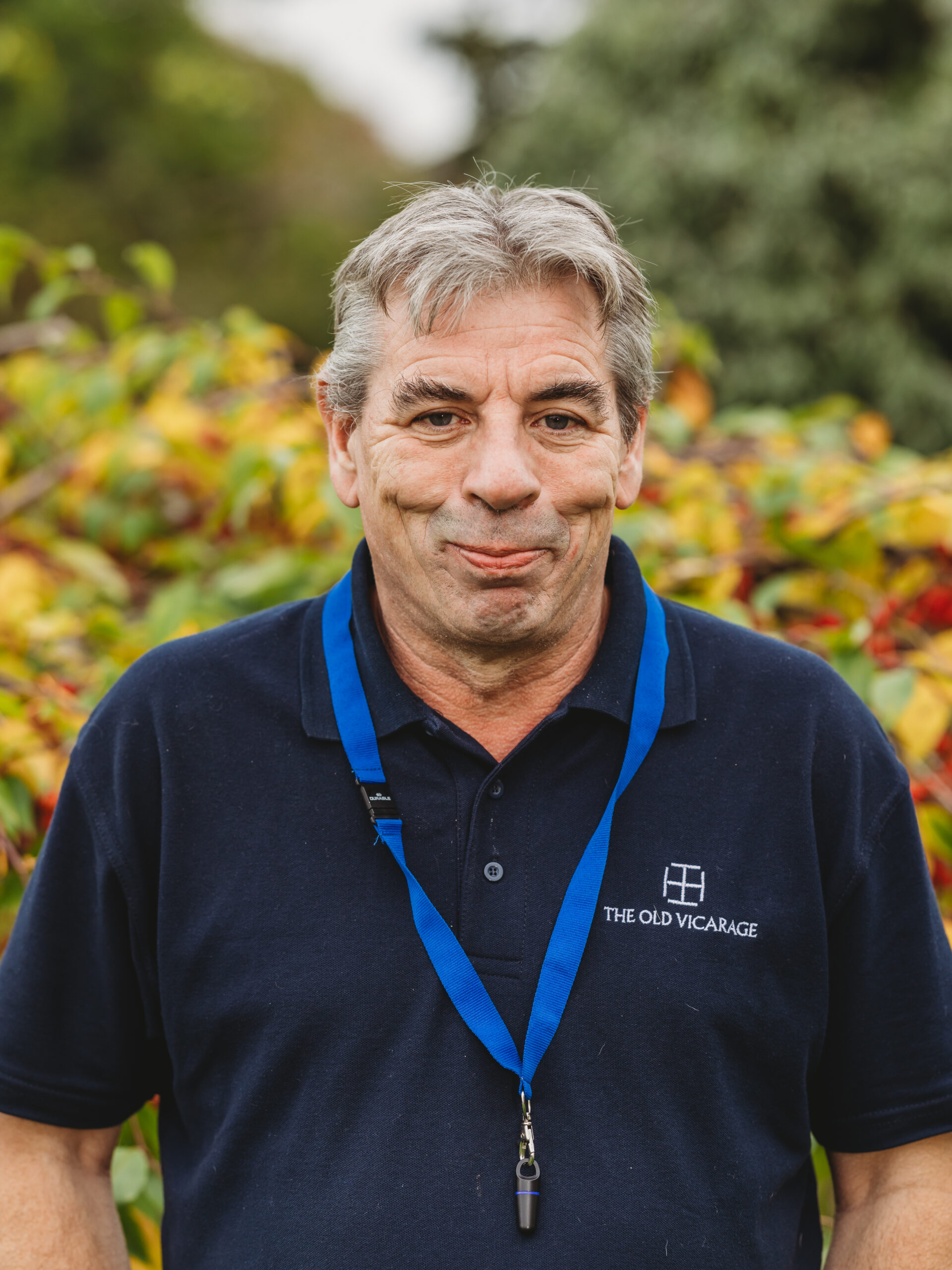 Staff member smiling outdoors among colorful foliage