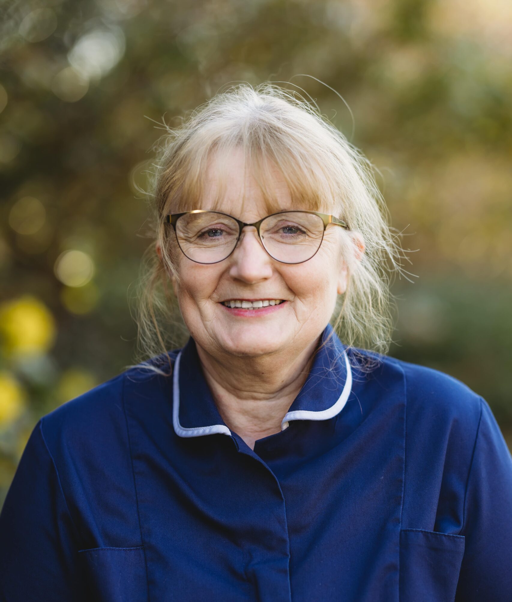 Smiling staff member in nursing home uniform outdoors