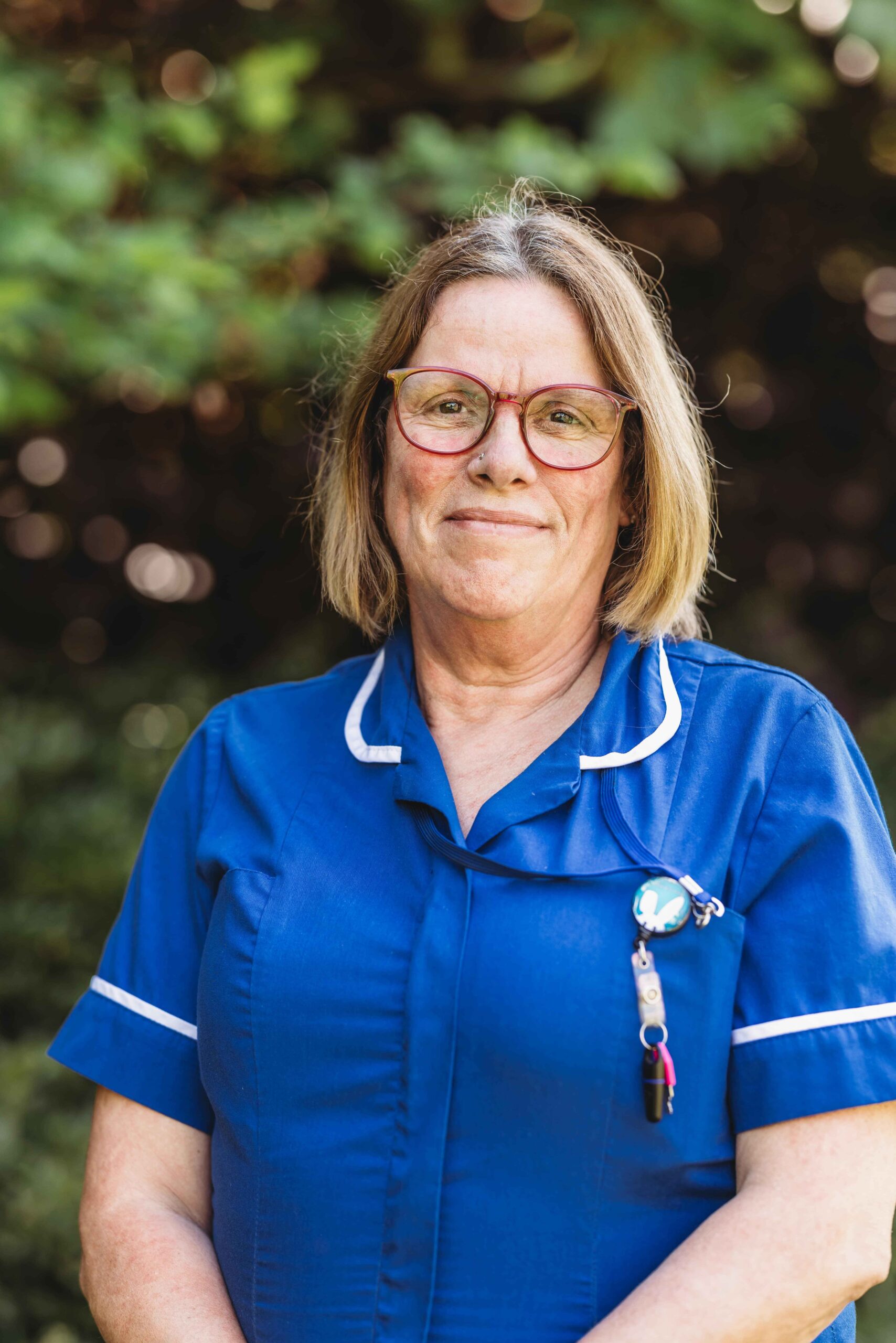 Nurse in blue uniform smiling outdoors