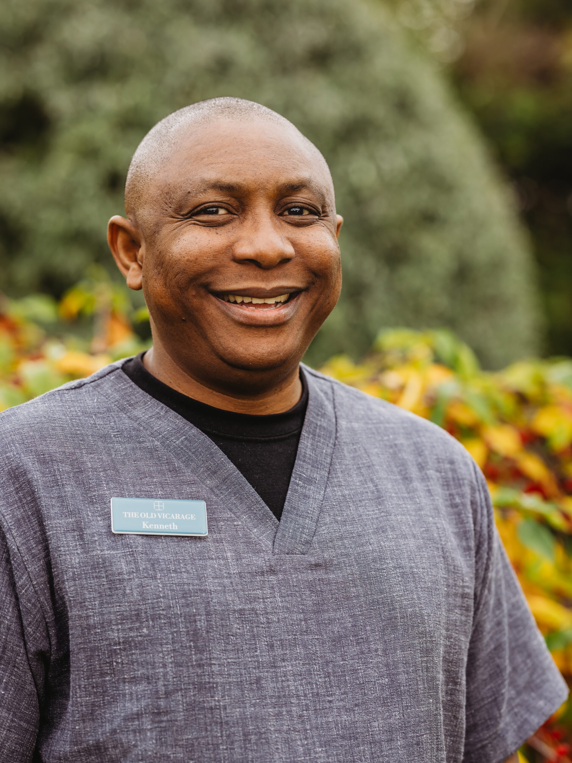 Staff member smiling in an outdoor garden setting