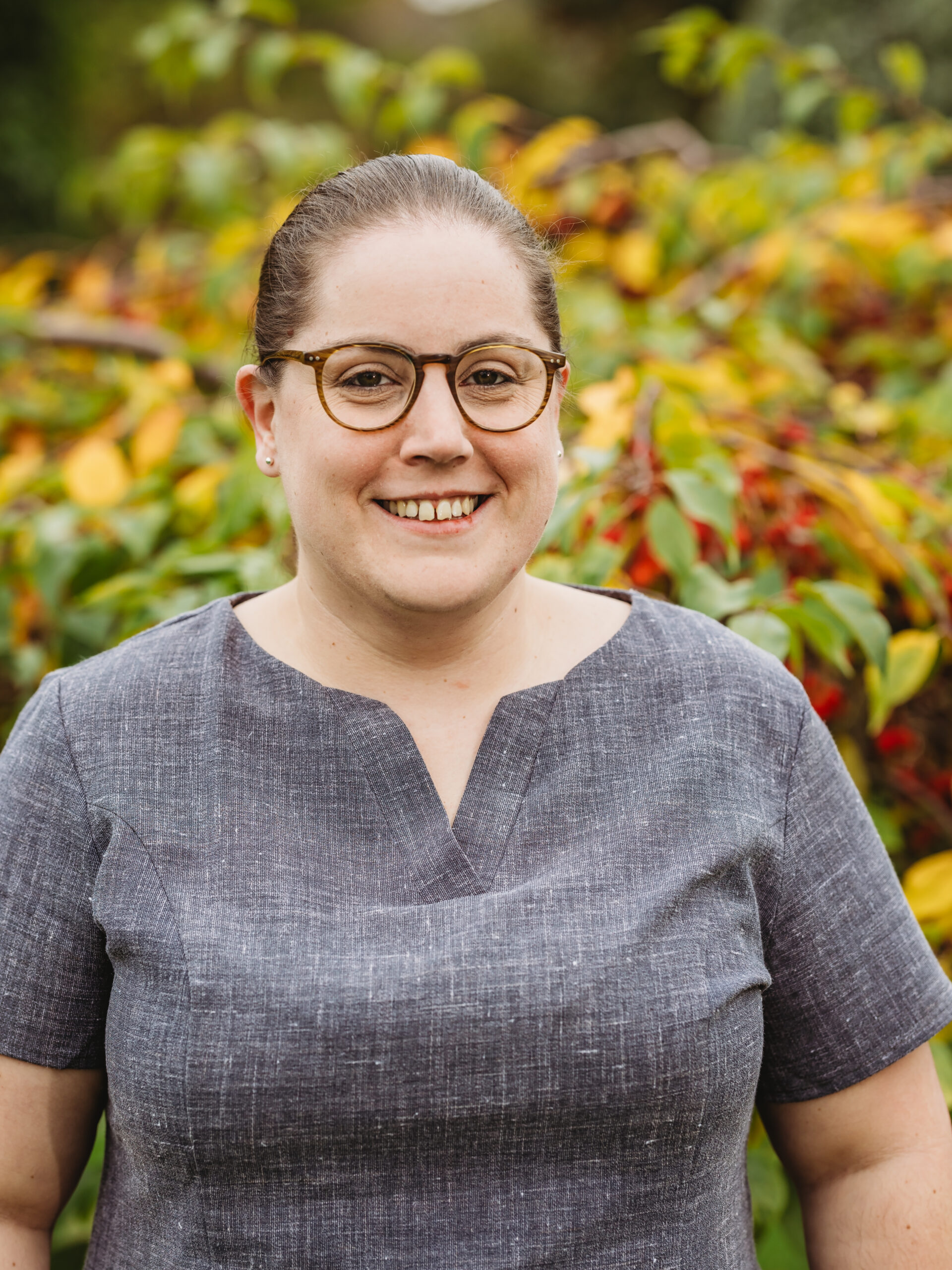 Staff member smiling with colorful foliage behind