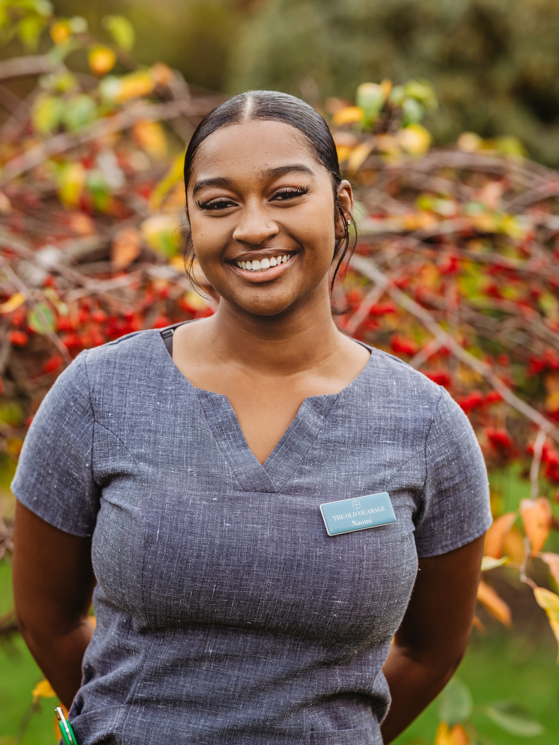 Staff member smiling in a garden setting.