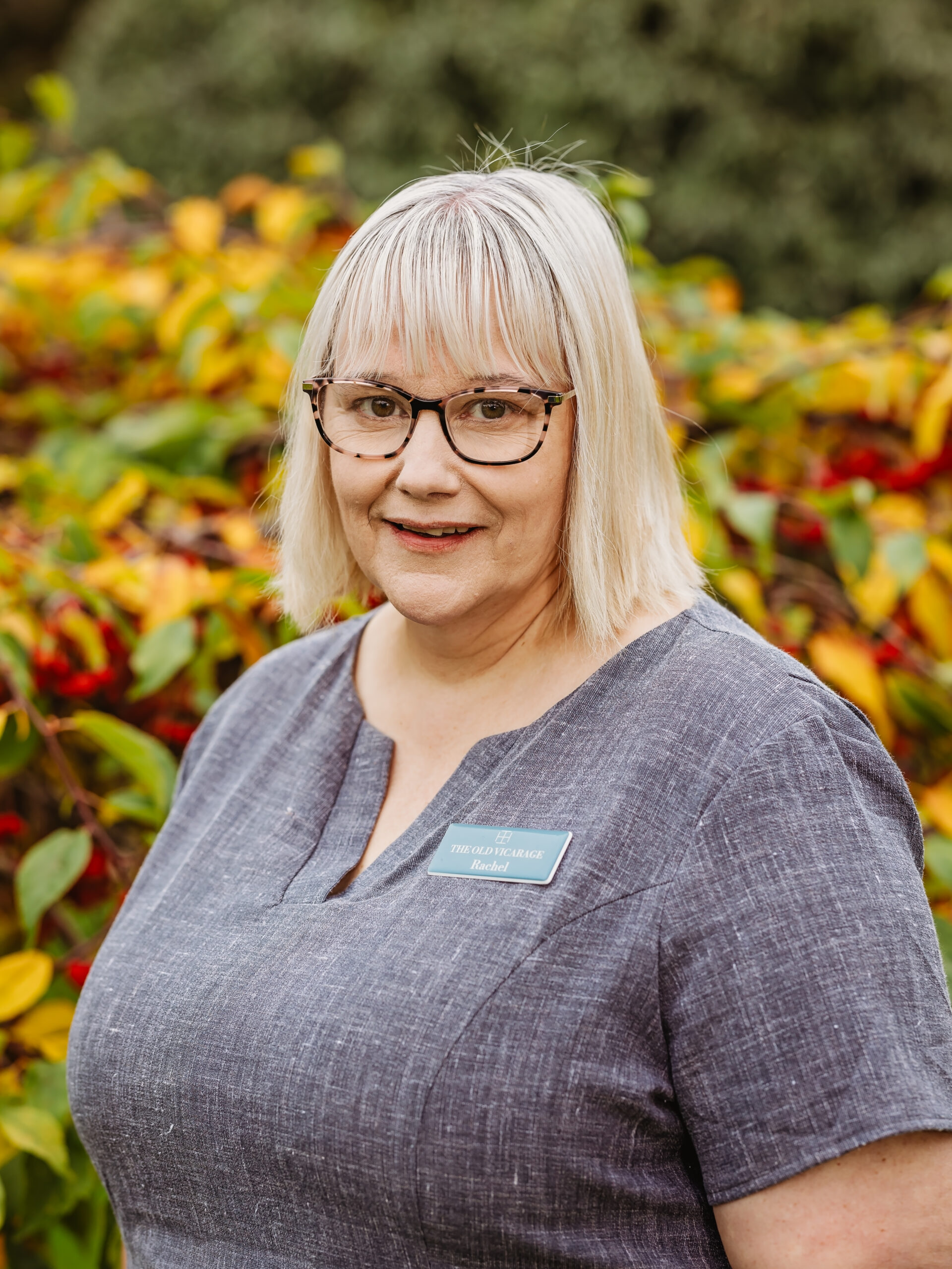 Staff member in front of vibrant foliage.