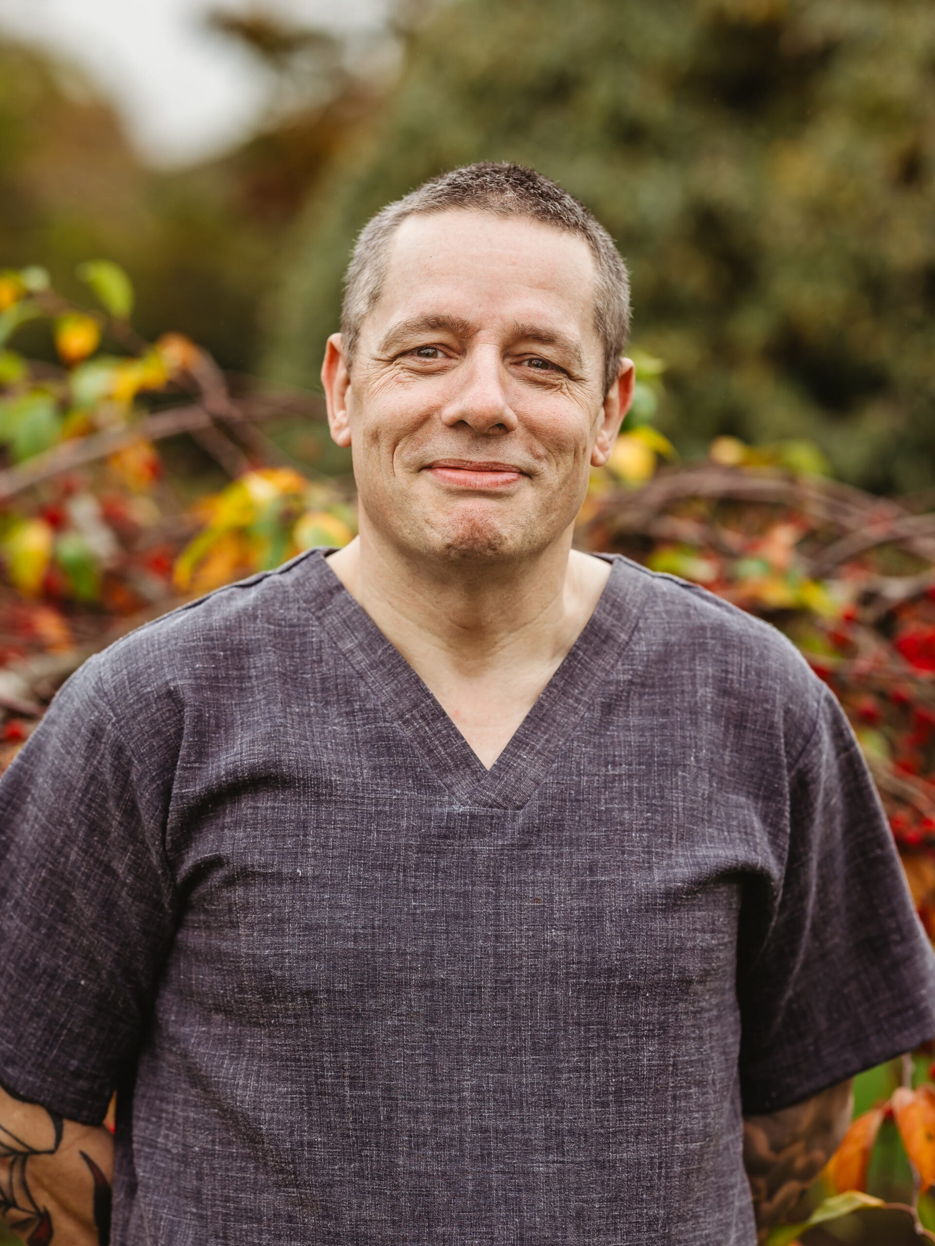 Staff member smiling in an outdoor garden area.