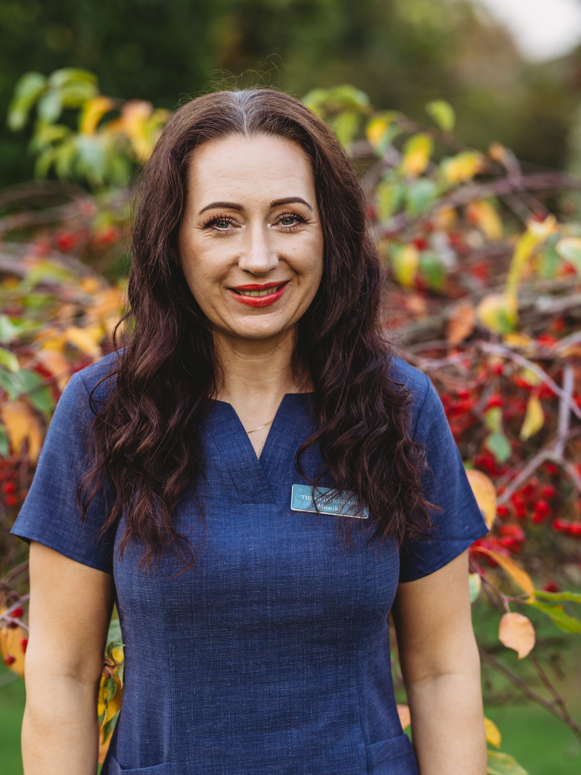 Staff member in front of autumn foliage.