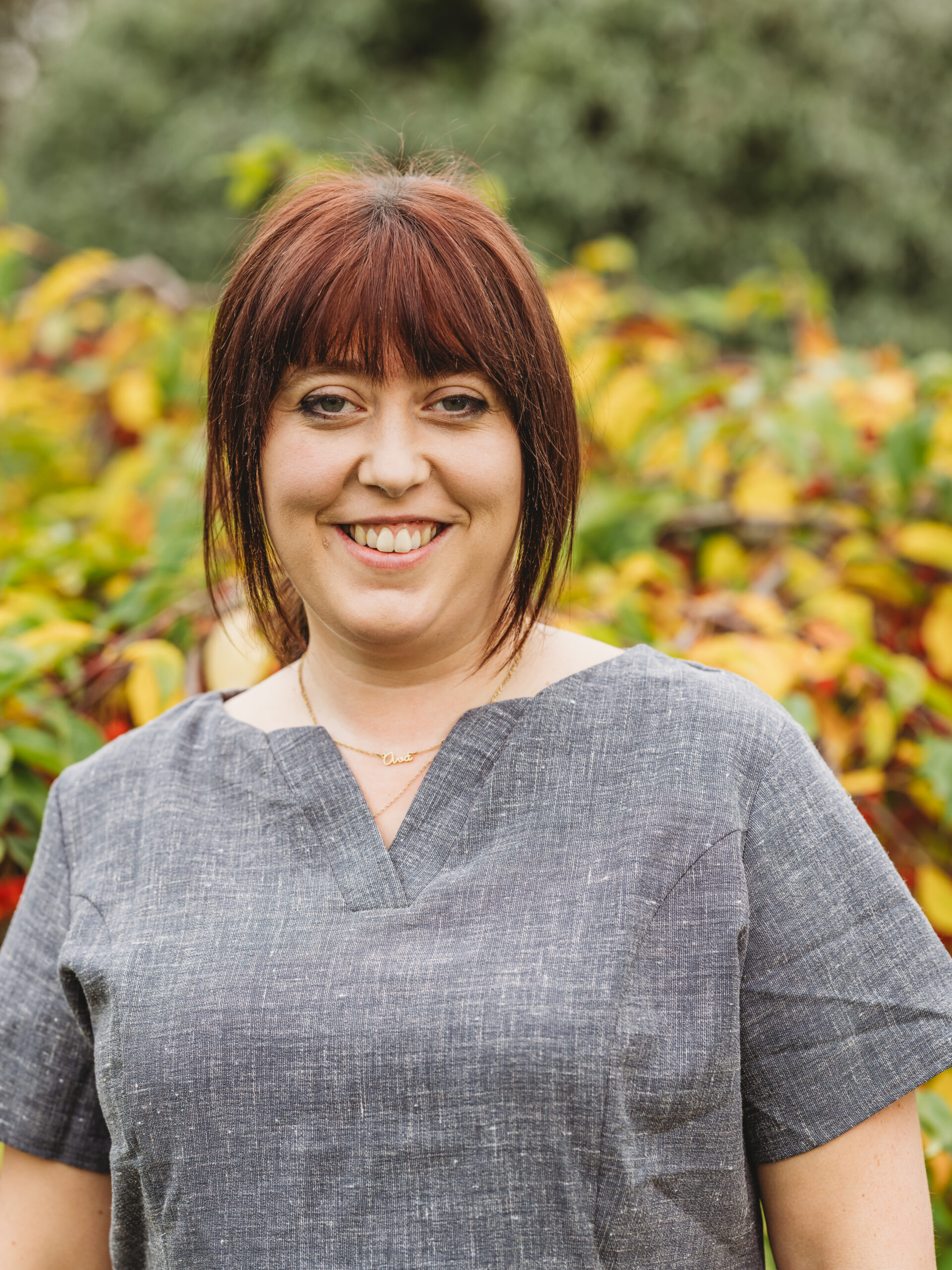 Staff member smiling in a garden setting.