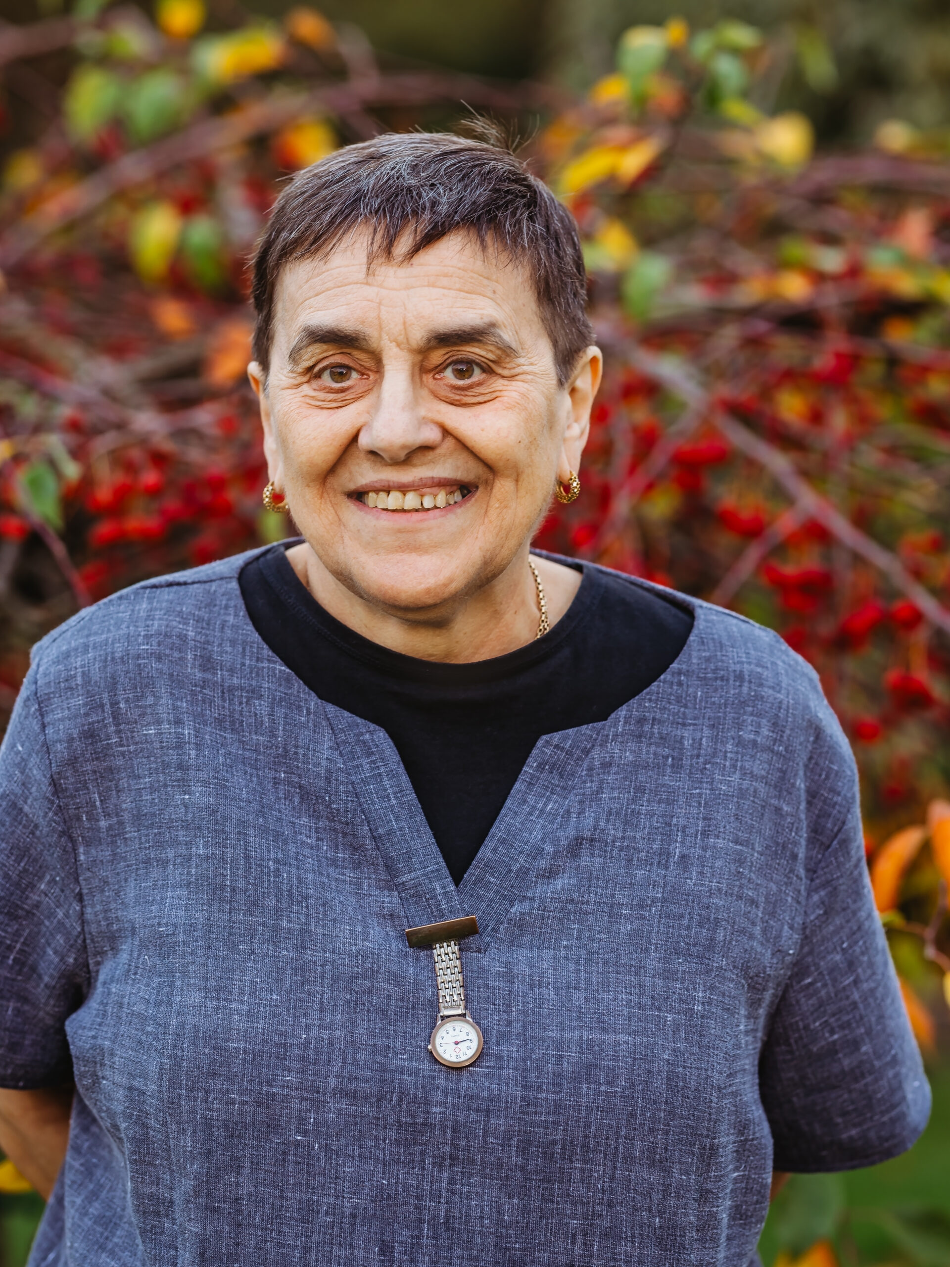 Woman smiling in front of colorful foliage.
