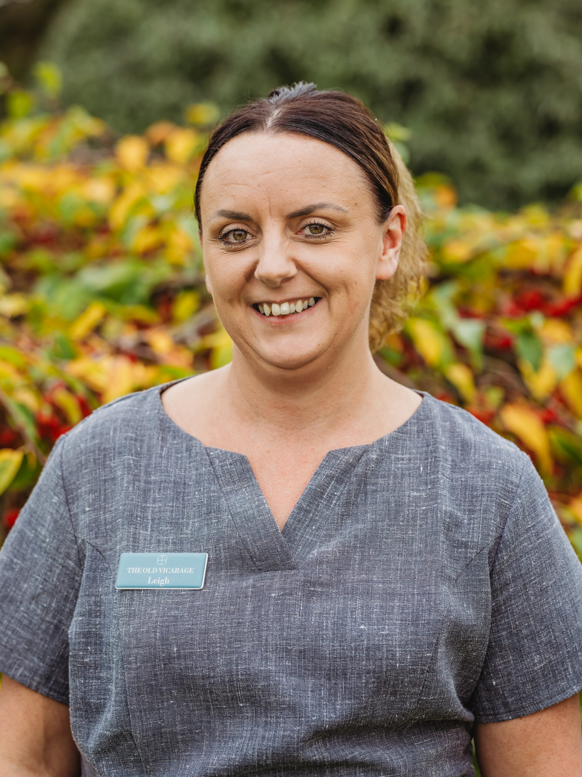 Staff member smiling outdoors with colorful foliage
