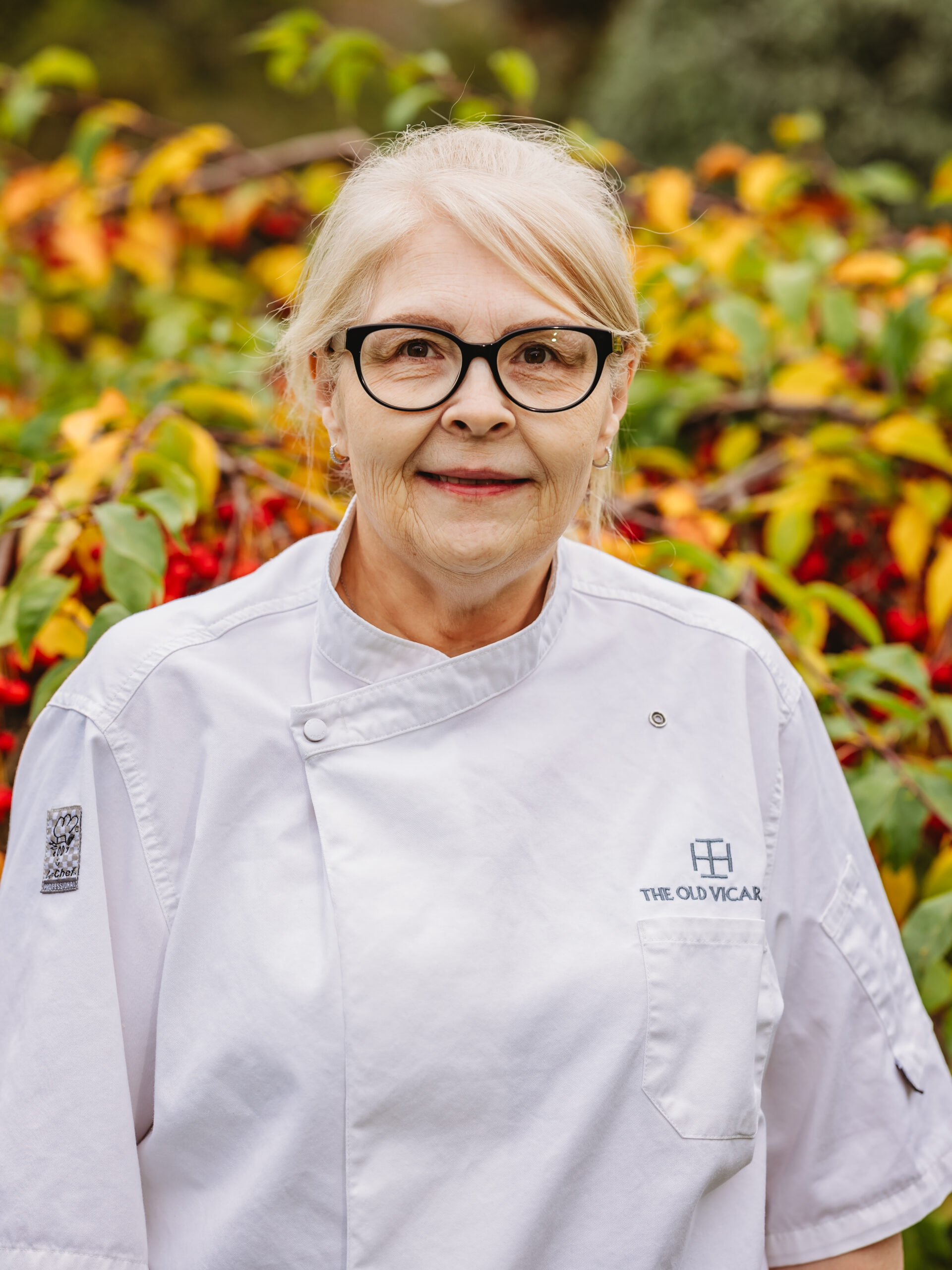 Chef in uniform with colorful foliage background.