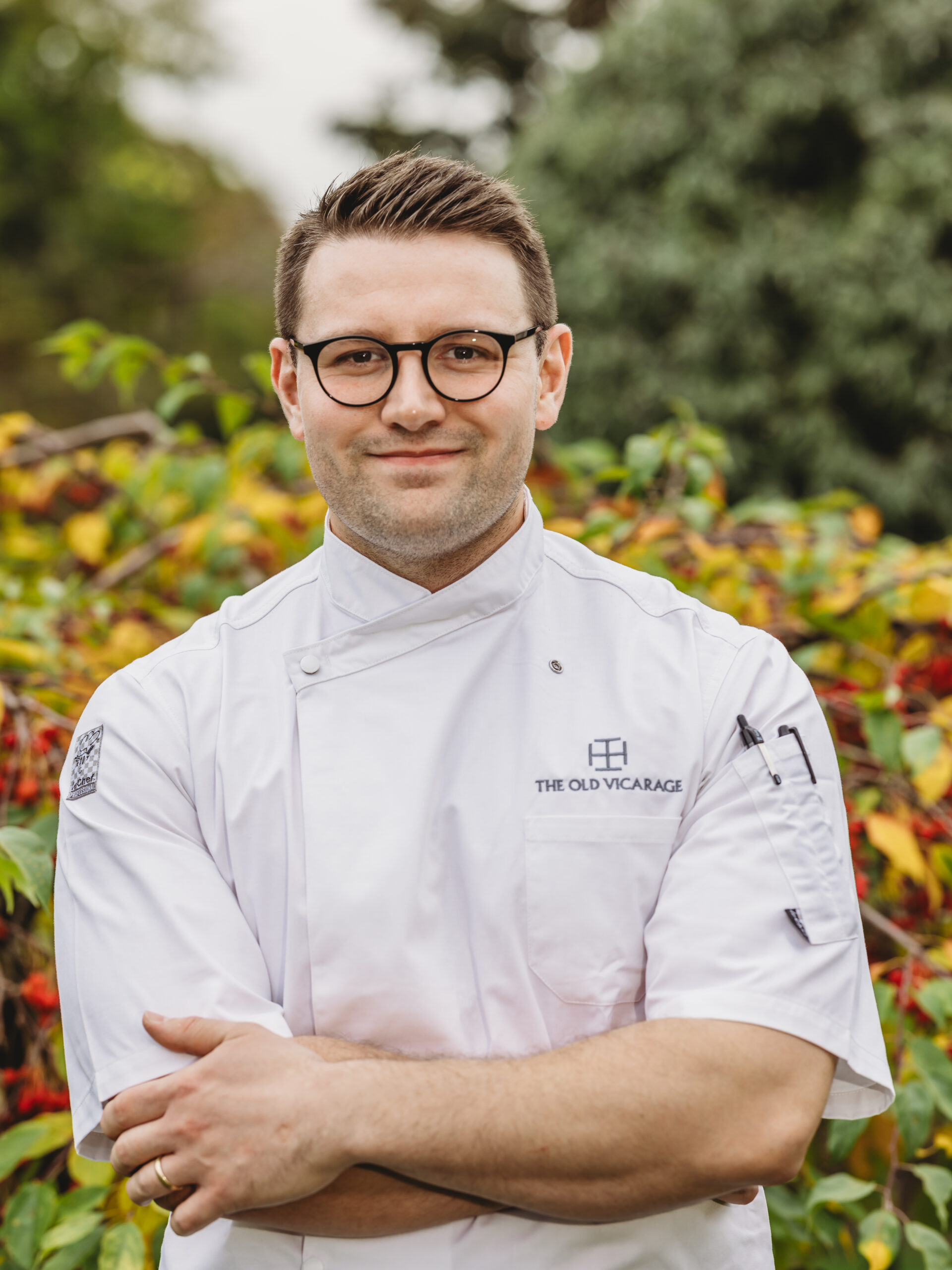 Chef in a white uniform outdoors, smiling