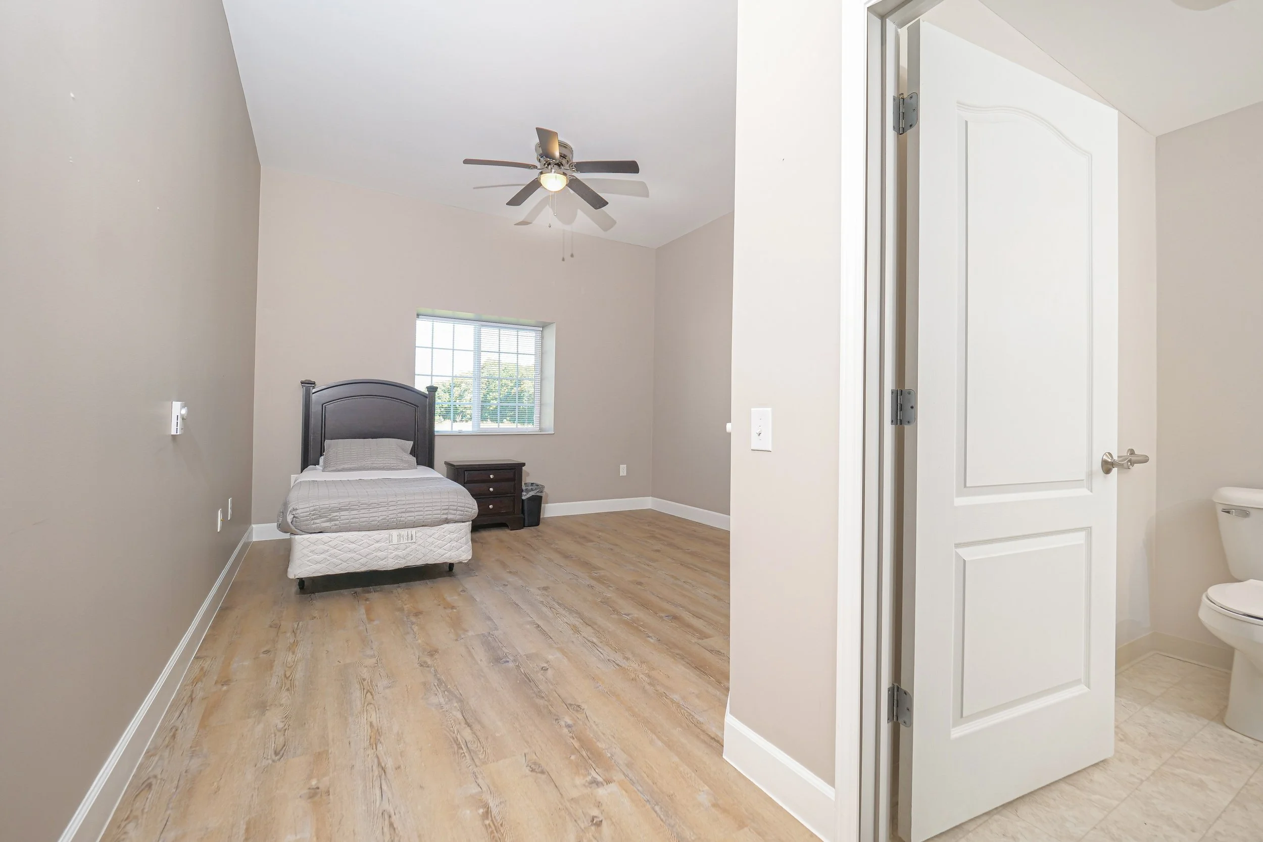 A private resident room with a bed and dresser.