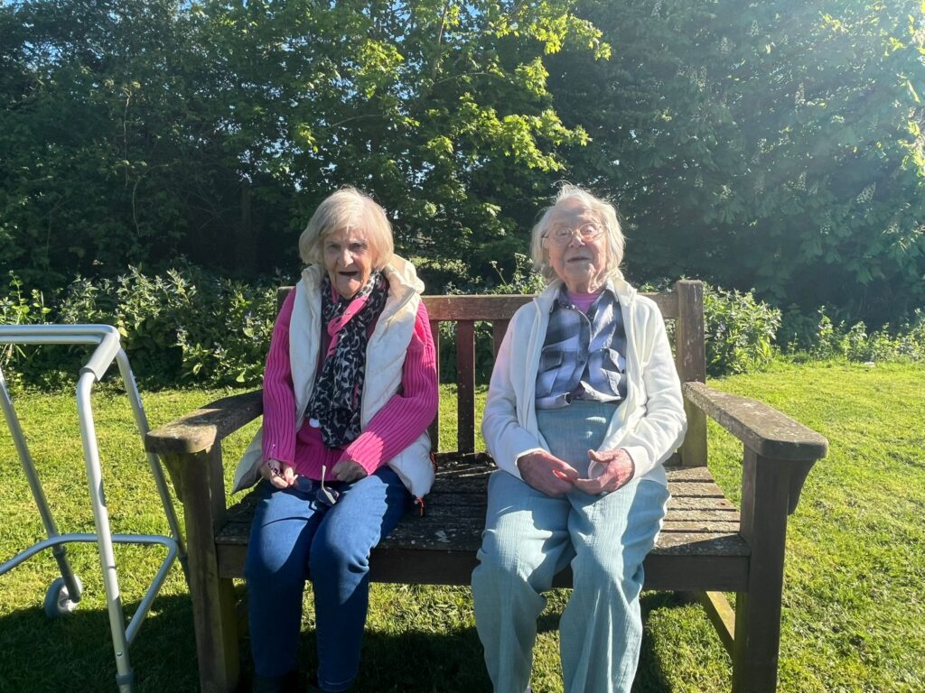 Two elderly women sitting on a bench outdoors