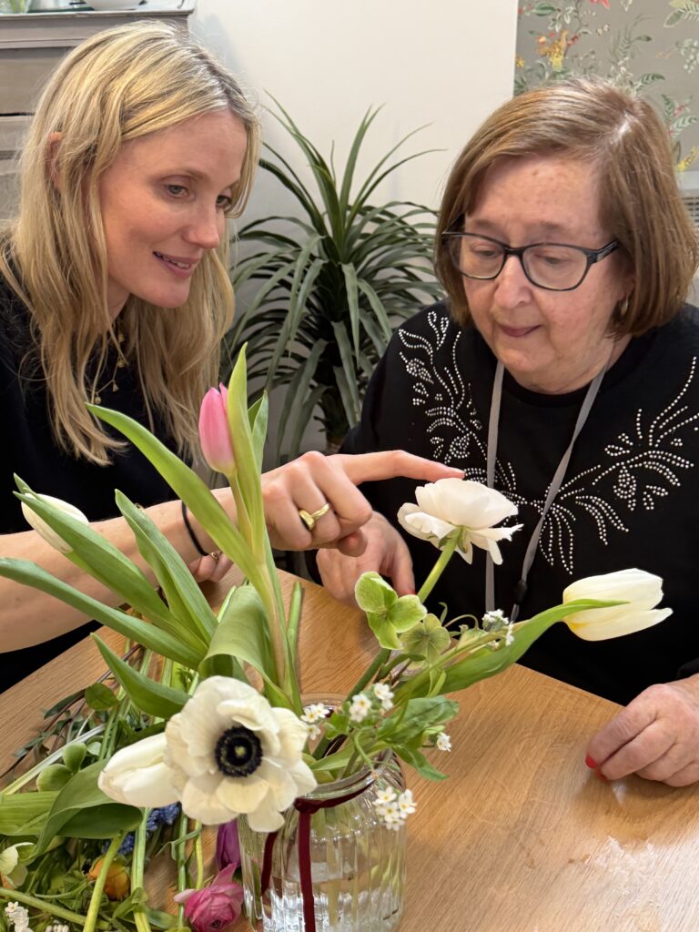 Resident and staff engaging in flower arranging activity.