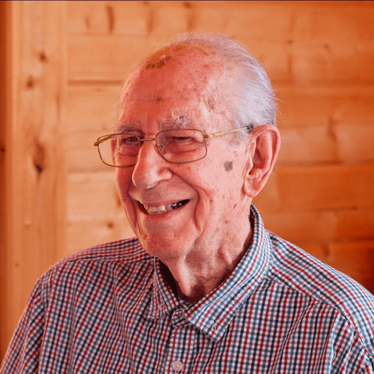 Elderly man smiling in a cozy setting.