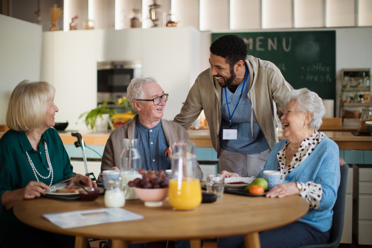 Residents and staff sharing a meal and laughter.