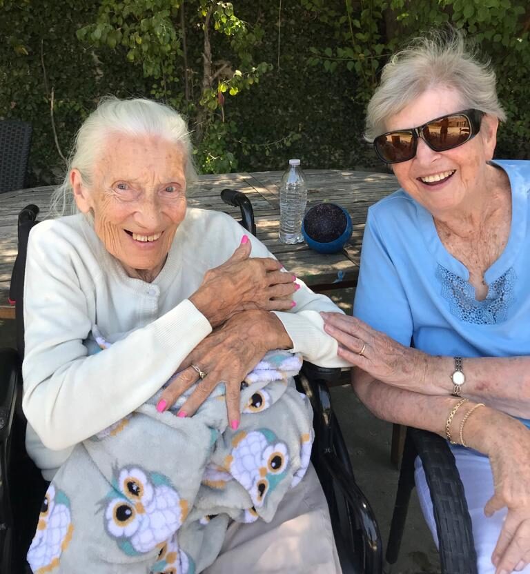 Two elderly women smiling outdoors.