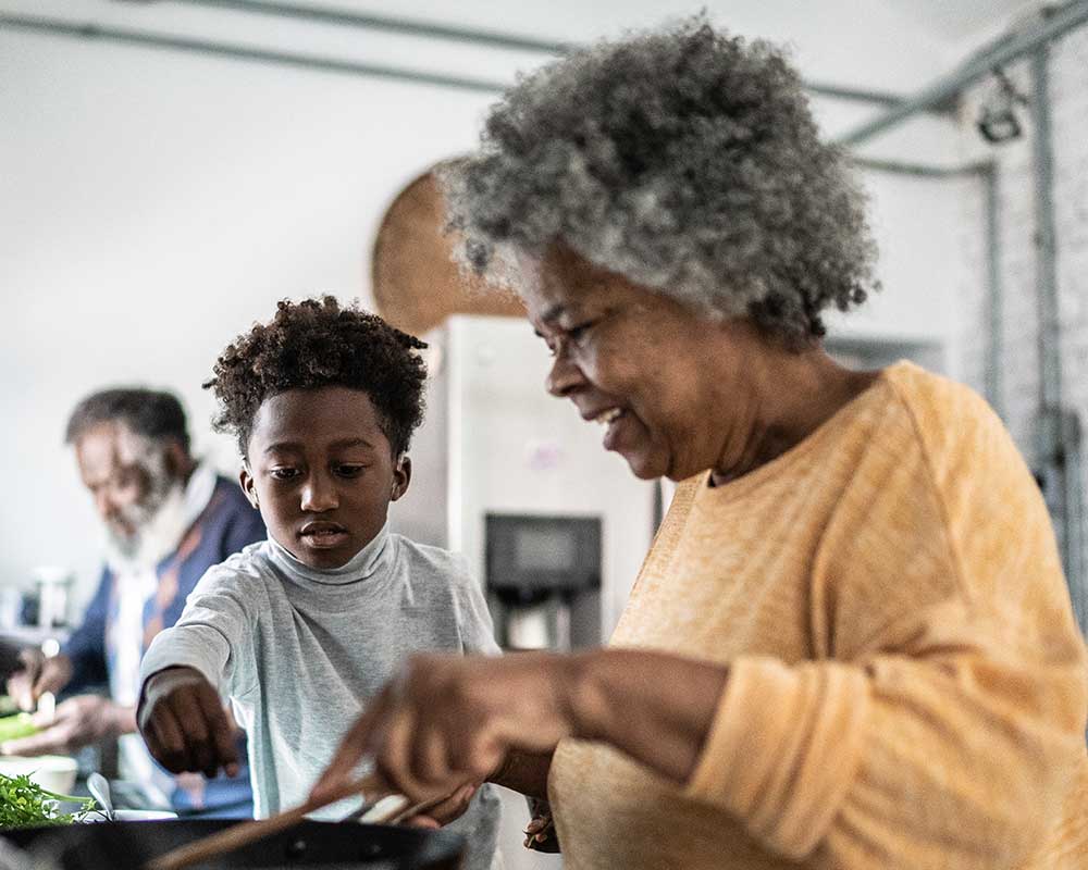 A resident cooking with a child in a kitchen