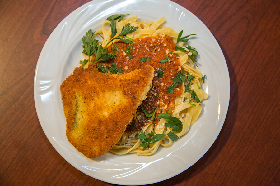 Plate of pasta with marinara sauce and breaded fish