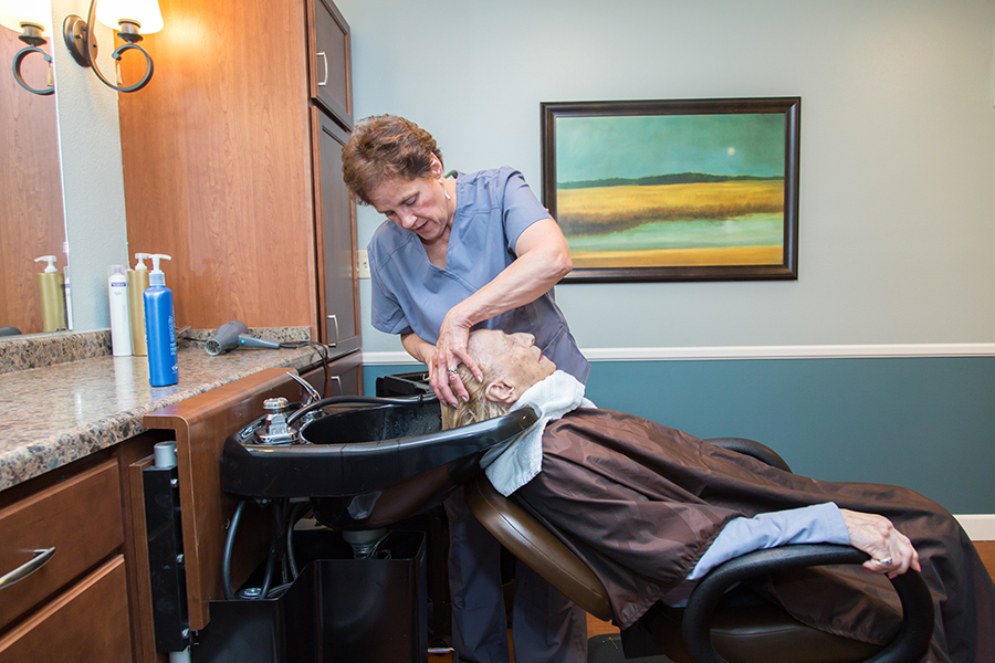 Staff assisting a resident with hair care in the salon