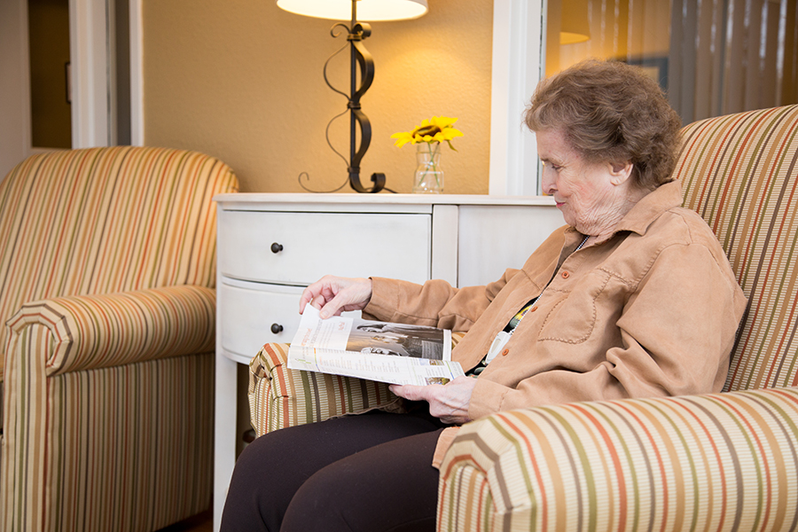 A resident reading a magazine in a cozy chair