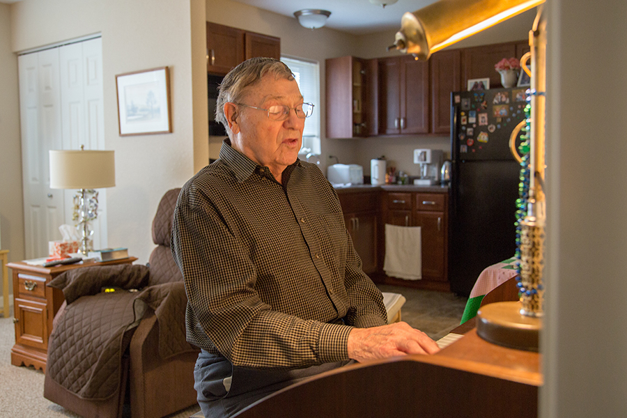An elderly man playing piano in a cozy living space
