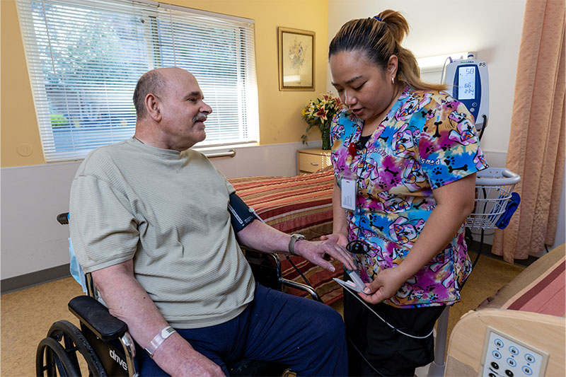 A caregiver checking a resident's vitals in their room