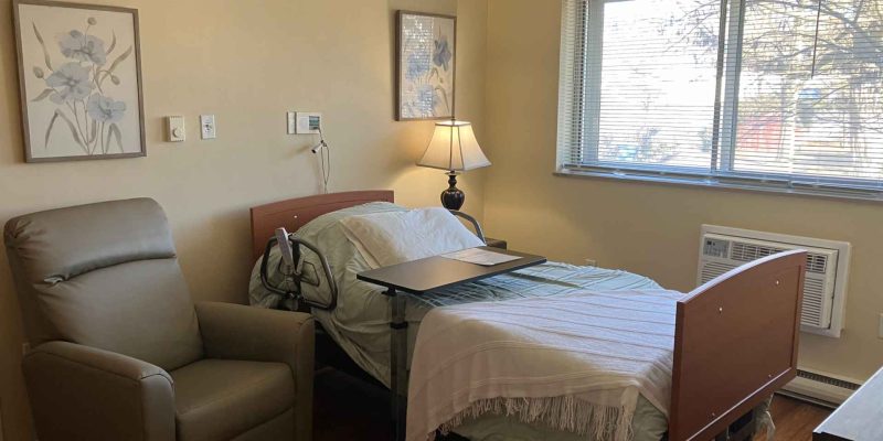 Cozy resident room with bed and armchair.