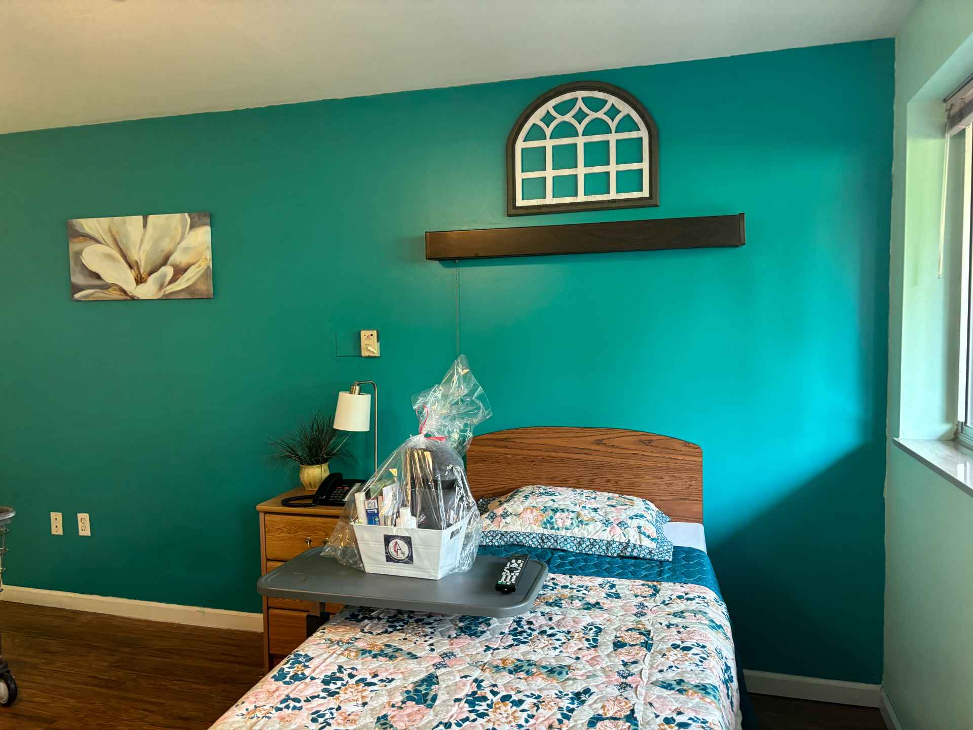 Cozy bedroom with teal walls and a floral bedspread.