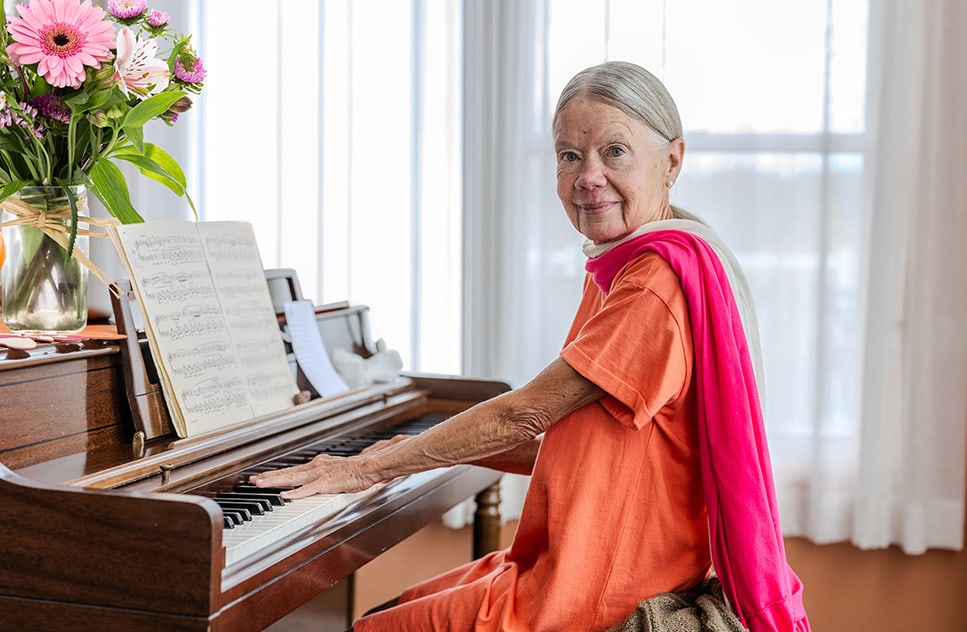 Senior resident playing piano in a bright room