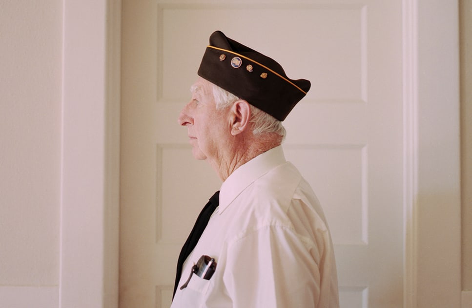 An elderly man in military attire standing indoors