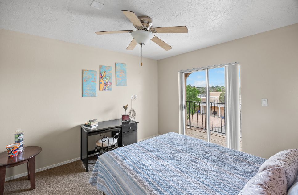 Brightly lit bedroom with a balcony and desk