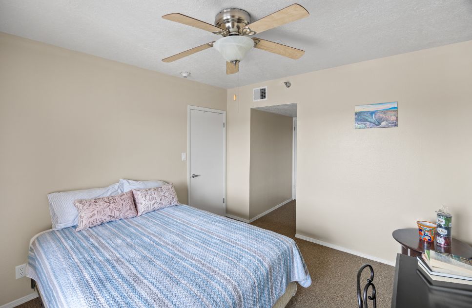 A tidy private resident room with a bed and a ceiling fan.