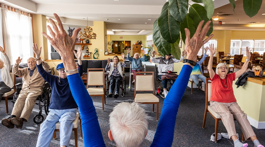 Residents participating in a seated exercise class in the activity room