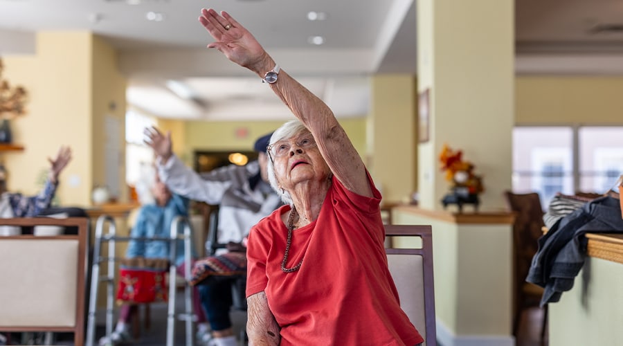 Senior resident raising hand during an activity in a common area